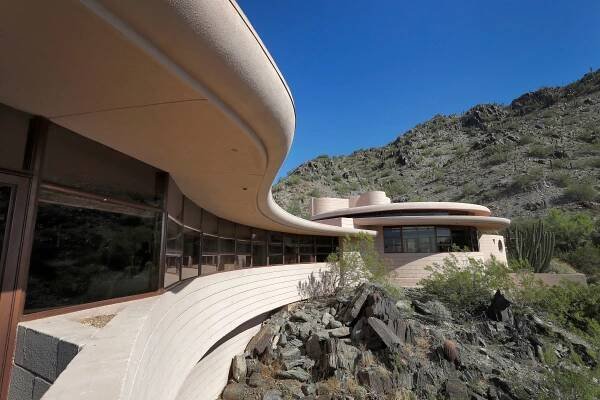 Frank Lloyd Wright’s Norman Lykes house in Phoenix, Arizona, which just went back on the market for $8M. The exterior shows a swooping curved patio towards a circular room.