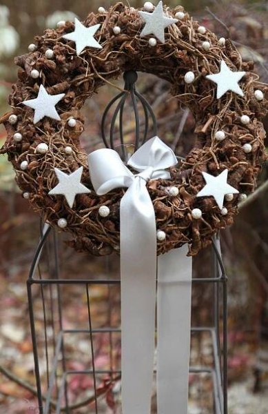 a wreath with white stars on it and a bow tied to the front is sitting in a birdcage