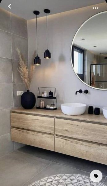 a bathroom with two sinks and a large round mirror