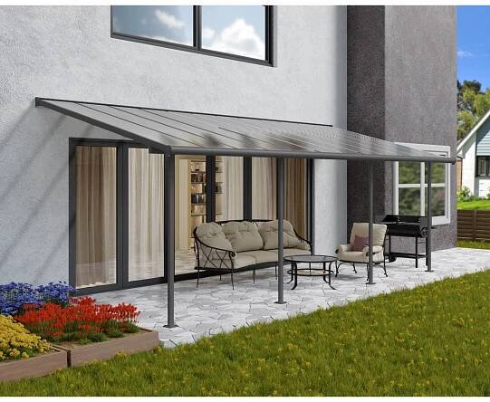 Graue Palram Canopia Terrassenüberdachung Sierra (739x295cm) am Haus mit Gartenmöbeln.
