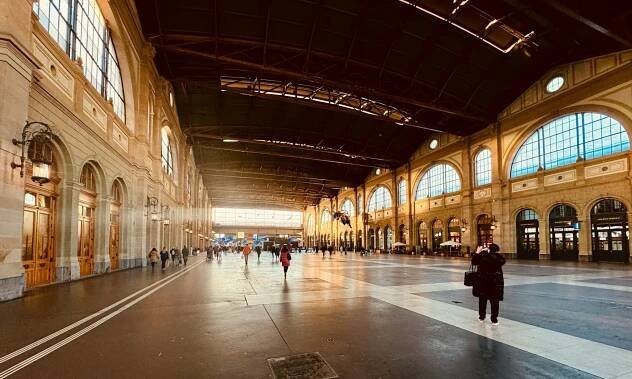 Wide-angle interior shot of Zurich's main train station, highlighting its grandiose architecture with high arched ceilings, classical columns, and expansive hallways. Zurich Hauptbahnhof is where you’ll start your layover in Zurich.‍