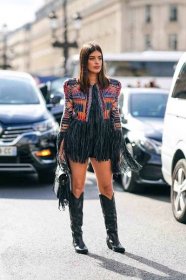 Wearing black cowboy boots, Aida Domenech shows how to style cowboy boots with fringe, one cowboy boots outfit idea for 2023.