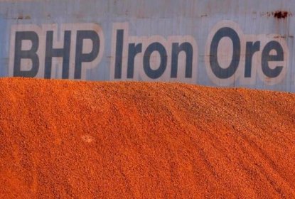 A BHP Billiton sign is visible behind a pile of iron ore at the company's loading facility in Port Hedland