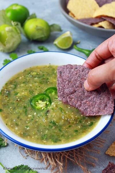 Dipping blue corn tortilla in roasted tomatillo salsa.