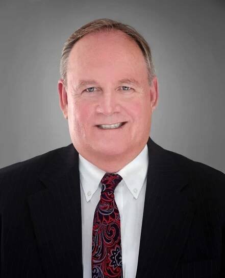 A man in a suit and tie is smiling for the camera.