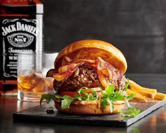 A bacon and caramelized onion burger paired with a rocks glass of Jack Daniel's. Photography by Alex Crawford.