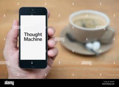 A man looks at his iPhone which displays the Thought Machine logo (Editorial use only). Stock Photo