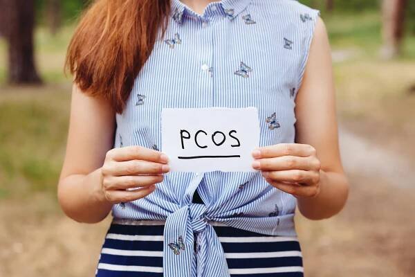 women with written sign that says PCOS (polycystic ovarian syndrome)