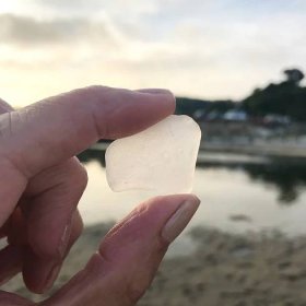 Searching for sea glass holding up into sunset