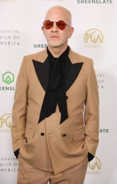 Ryan Murphy on the red carpet in a tan suit with black lapels and a large black bow tie