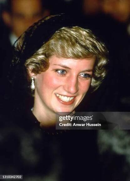 Diana, Princess of Wales, wearing a black lace dress designed by Catherine Walker and a mantilla veil to cover her hair, smiles as she visits The...