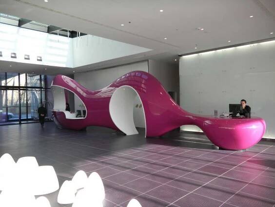 a man sitting at a desk in the middle of a room with pink and white furniture