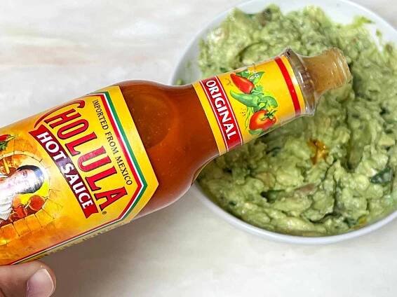 Pour Cholula Hot Sauce into a bowl of guacamole