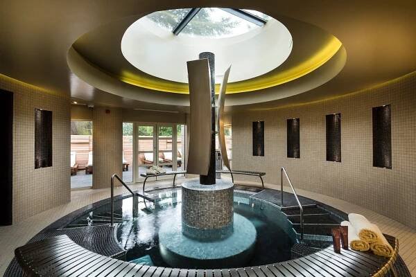 indoor spa area featuring a circular hot tub and ambient lighting at down hall