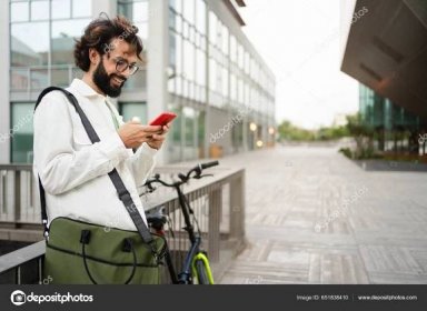 Stáhnout - Mladý příležitostný obchodník pomocí mobilního telefonu stojící vedle kola ve městě — Stock obrázek