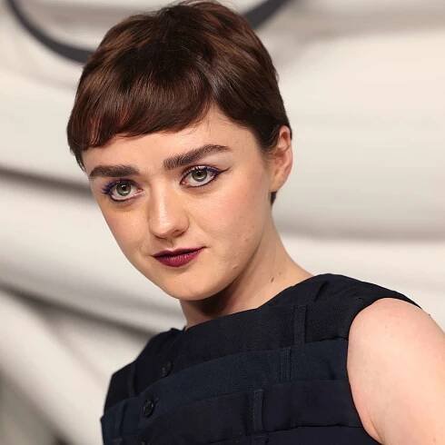 Maisie Williams at Paris Fashion Week with pixie hair cut, black eyeliner, wine lips, black top