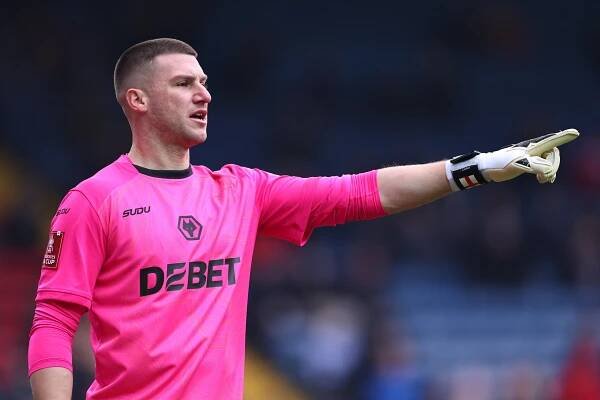 Sam Johnstone of Wolverhampton Wanderers in a pink goalkeeper jersey, pointing.