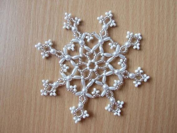 a white beaded snowflake sitting on top of a wooden table