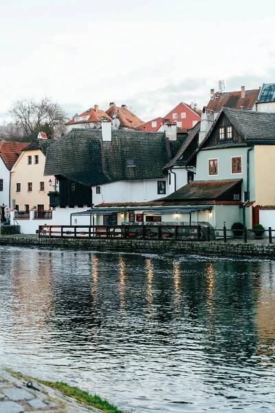 bezplatná Malebný pohled na zimní Český Krumlov, zachycující historické domy u řeky odrážející se ve vodě. Základová fotografie