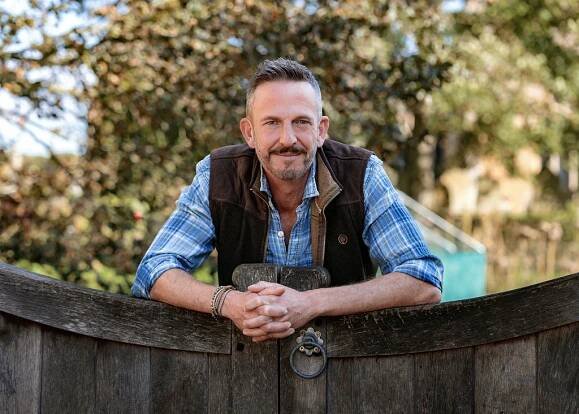 Man leaning on a wooden gate.