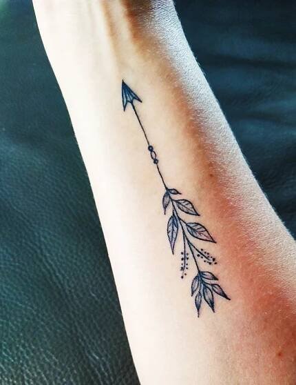 a woman's arm with an arrow tattoo on it