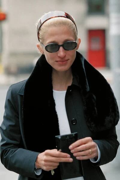 Carolyn Bessette-Kennedy walking outside and wearing a wide tortoiseshell headband in her hair.