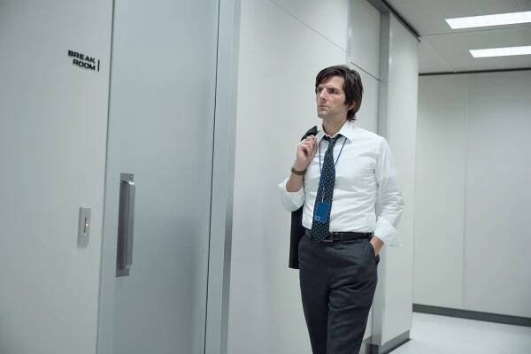 Adam Scott walks down an office hallway towards a door that says "break room."