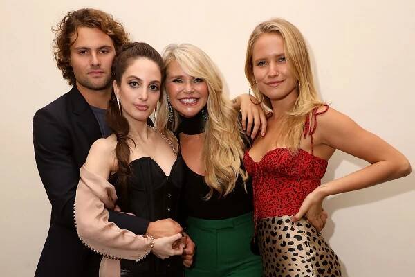 Christie Brinkley in a black top and green skirt, Alexa Ray Joel in a black bustier and beige wrap, Sailor Brinkley Cook in a red top and animal print skirt. Jack Brinkley Cook in a black blazer and black t-shirt.