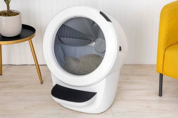 The Whisker Litter-Robot 4 on a floor between side table and yellow chair