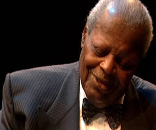 Oscar Peterson looking down at piano keys while playing