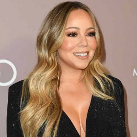 Mariah Carey wears a warm-toned medium blonde balayage curled hairstyle