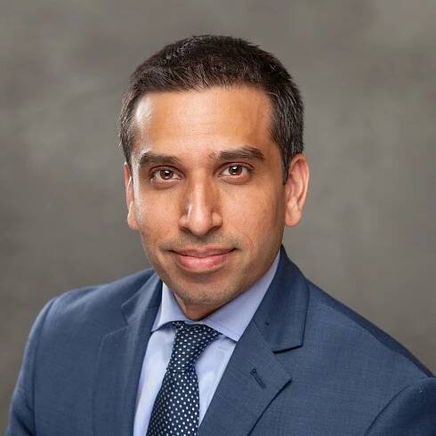A man in a suit and tie is smiling for the camera.