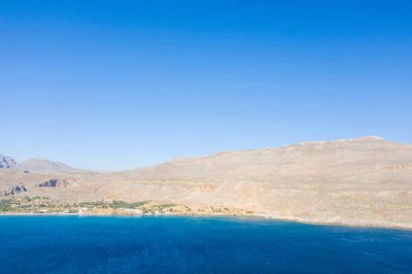 the sandy beach at the foot of the arid mountains , in europe, greece, crete, kato zakros, by the mediterranean sea, in summer, on a sunny day. - achaia - stock snímky, obrázky a fotky