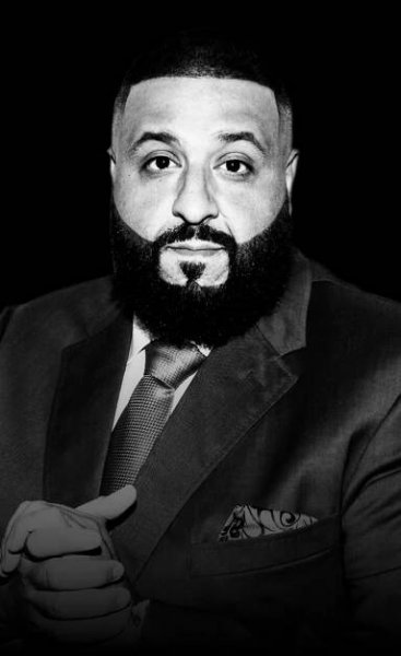 A black-and-white portrait of DJ Khaled with a well-groomed beard, wearing a suit and tie, looking confidently at the camera.