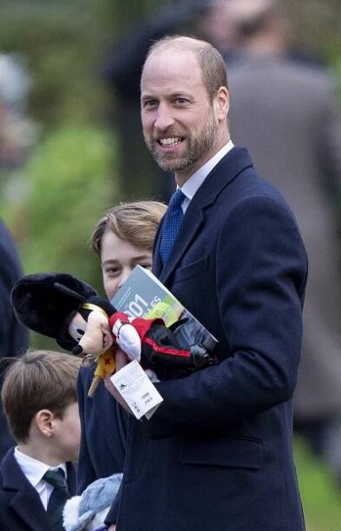 Prince William carrying stuffed toys and a book.