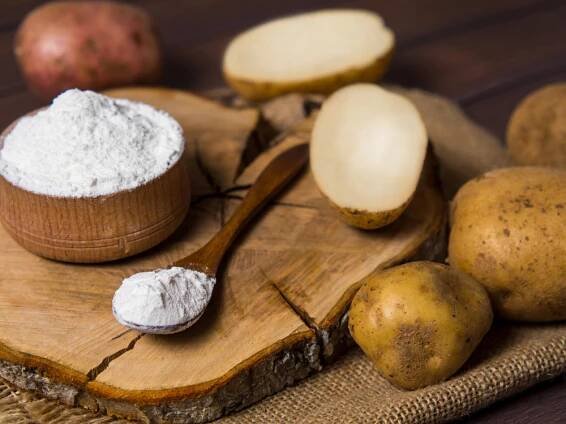 Potato starch with potatoes dark wooden background