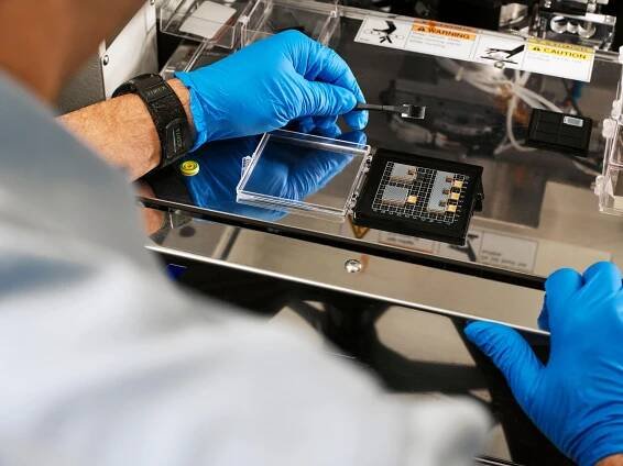 AI hardware - IBM researcher John Knickerbocker carefully handles polymer optical waveguide modules in the lab.