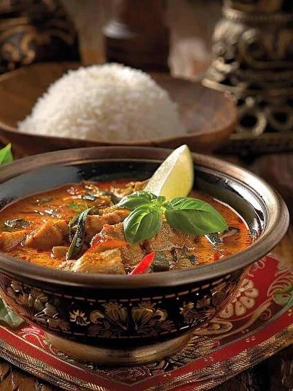 Panang Curry served in a bowl with steamed rice, garnished with fresh basil leaves.