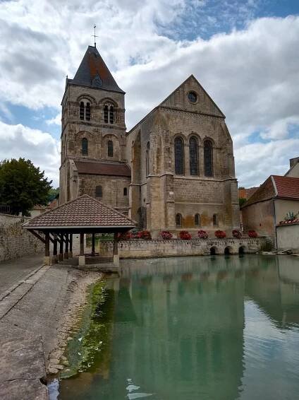 A church next to a river with a boat in the background, possibly a barge cruise.