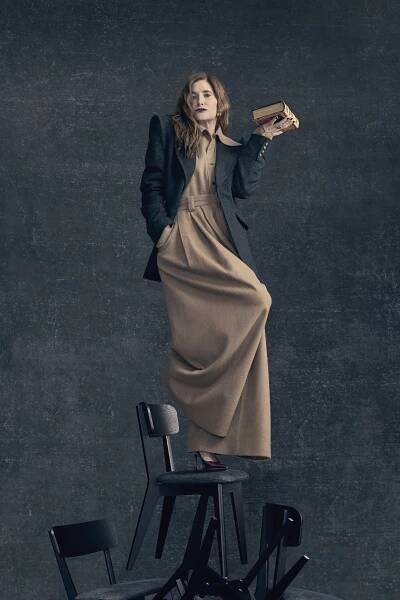 Kathryn Hahn standing on chairs.
