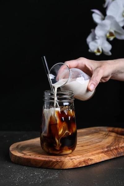 Vegan creamer being poured into a cold brew coffee.