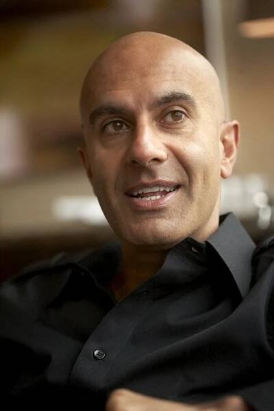 a balding man wearing a black shirt is looking at the camera with an intense look on his face