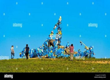 Men in the ritual circumnavigation of an Ovoo, a sacred stone heap used as place of worship in Mongolian religious tradition, Mongolia Stock Photo