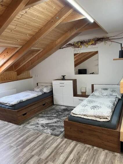 two beds in a large room with wooden ceilings at Apartmány Nová duha Vavřinec in Vavřinec
