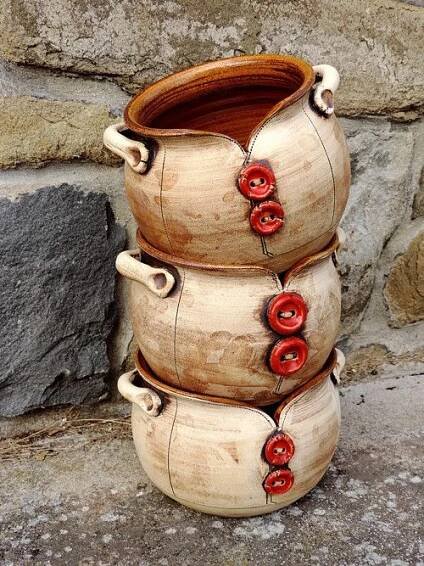 three wooden vases with red buttons on them sitting in front of a stone wall