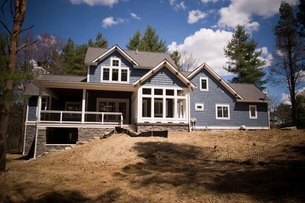 A large house with a lot of windows is sitting on top of a dirt hill