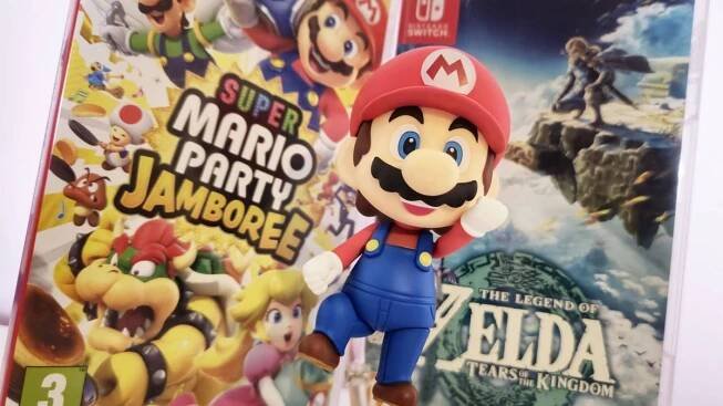 Photo of Mario jumping between copies of Super Mario Jamboree and Tears of the Kingdom on the Nintendo Switch, taken by writer Rosalie Newcombe.