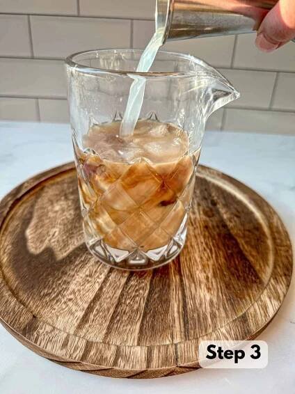 Vodka being poured into a clear cocktail shaker.