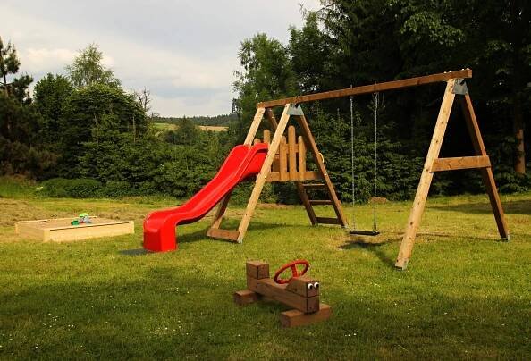 a playground with a red slide and a swing at Penzion Zámek Rozsochatec in Rozsochatec