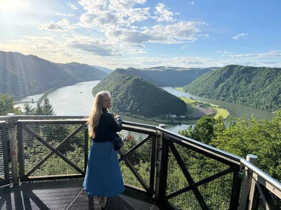 Woman on a viewing platform overlooking a river valley.